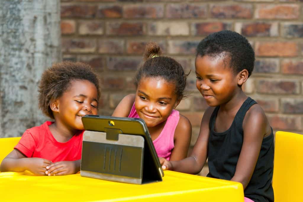 Children watching a tablet together promoting peace and unity.