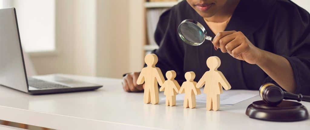 Child examining wooden figures with magnifying glass for peace and unity themes.